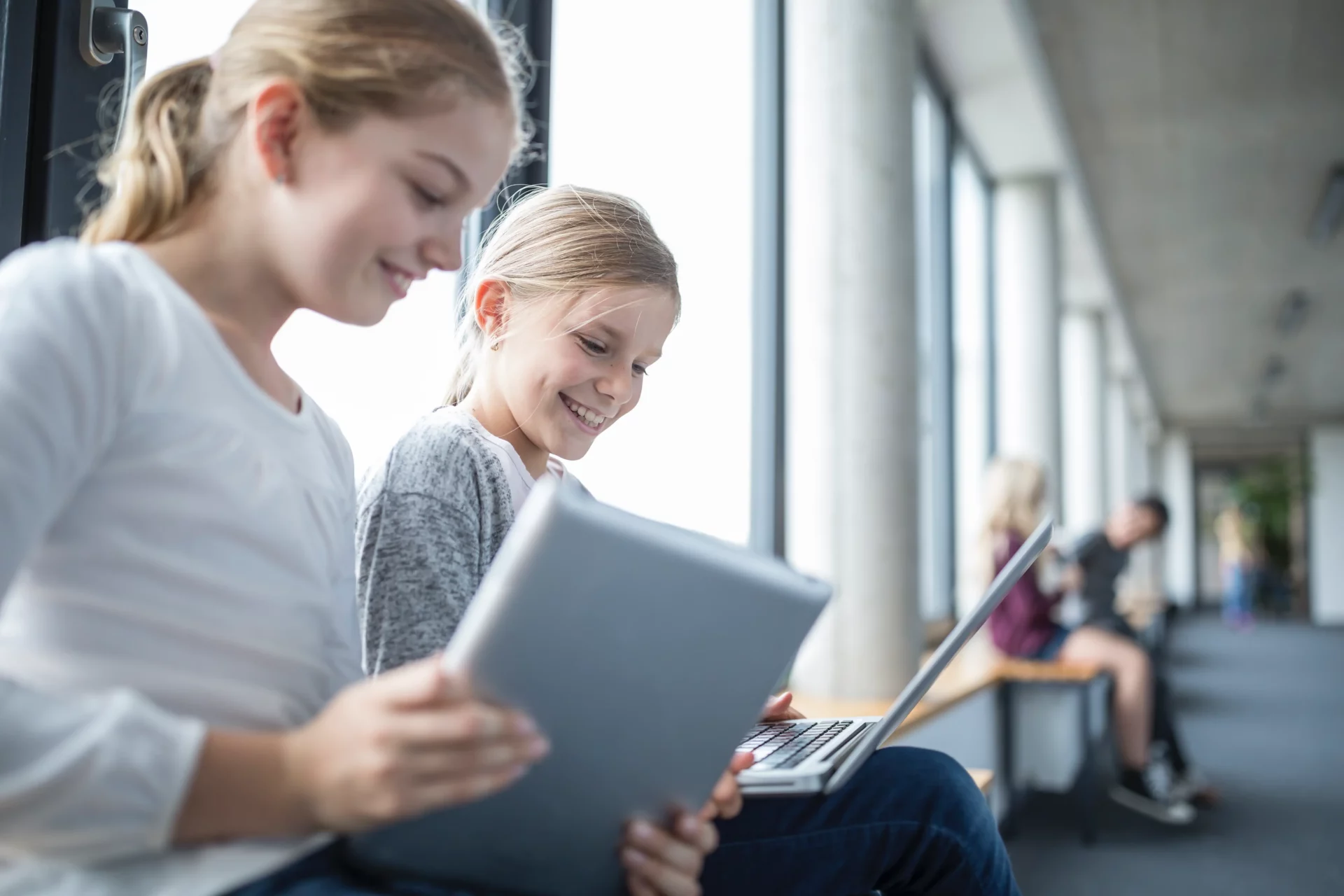 Deux filles rigolent en faisant leur devoir de manière digitale
